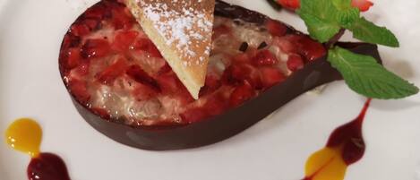 A dessert plate with a slice of cake, strawberries, and mint leaves.