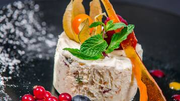 A dessert with berries and mint leaves on a dark surface.