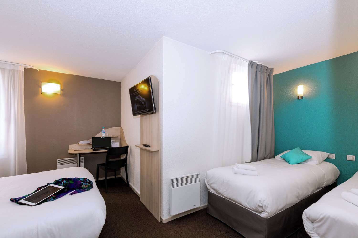 A hotel room with two beds, a desk, a computer, and a TV.