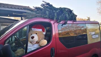 Een rode bus met een grote teddybeer met een kerstmuts op de passagiersstoel.