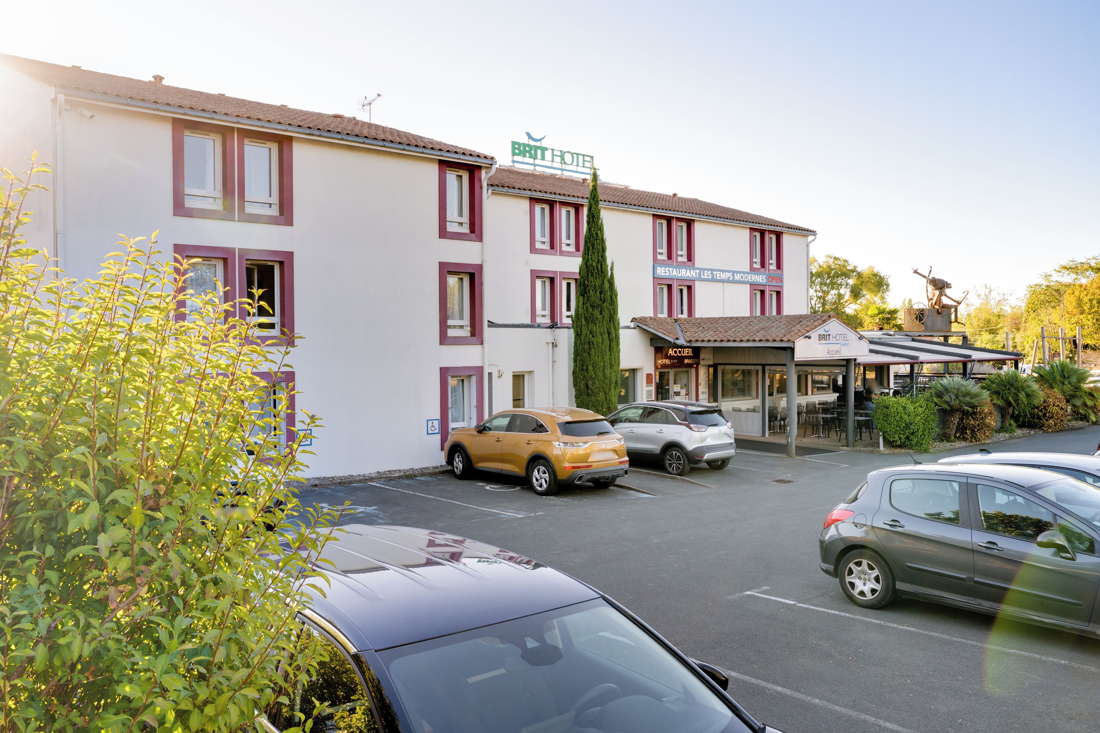 Un hotel con estacionamiento, restaurante y una estatua.