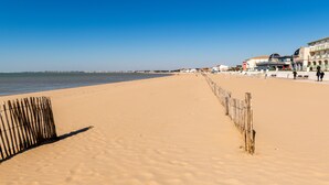 A beach with a wooden fence, buildings, and a clear sky. - Brit Hotel La Rochelle Périgny (Perigny)