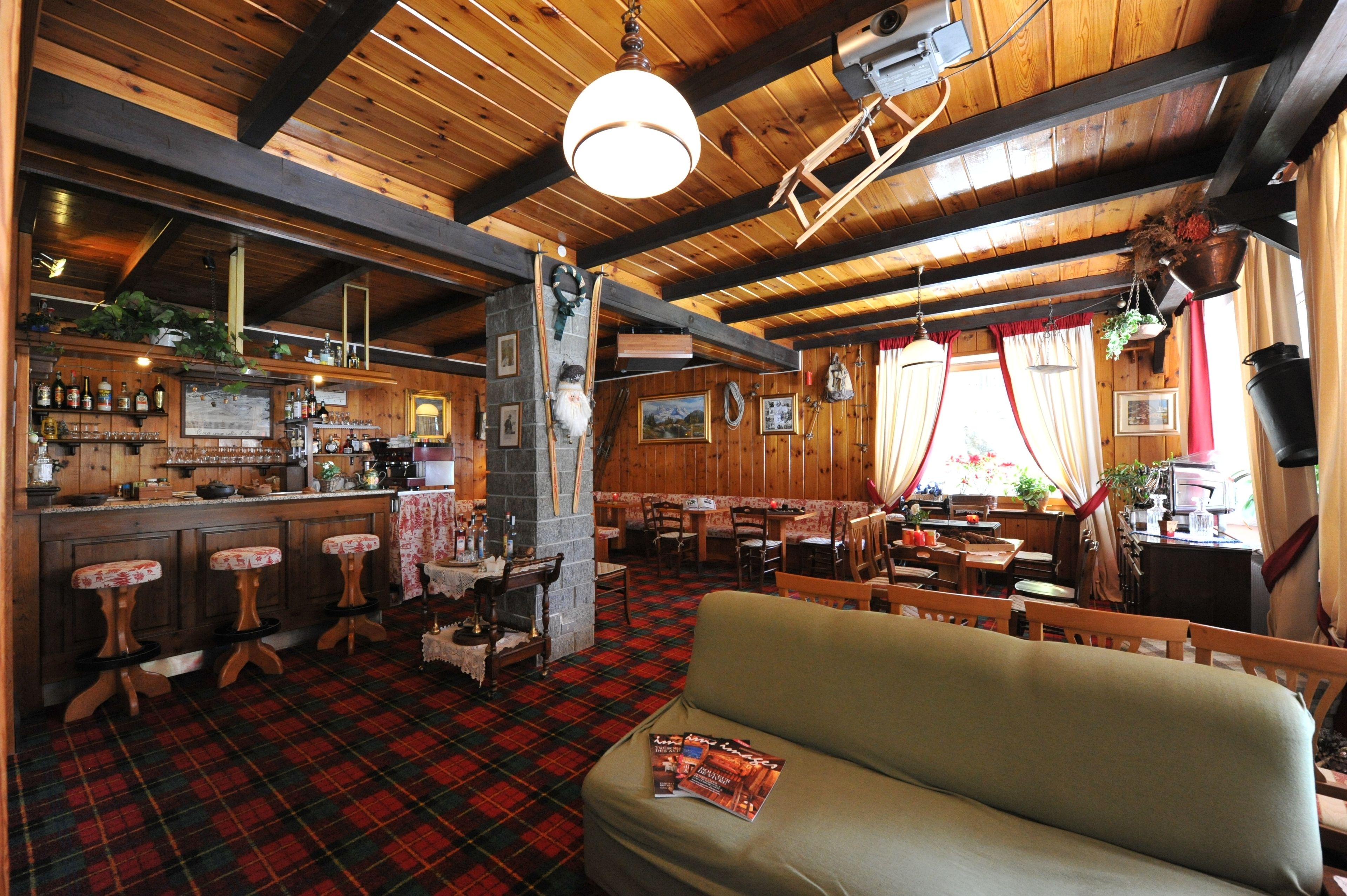Un pub chaleureux avec un décor intérieur en bois, un bar et un espace salon agrémenté d’un tapis à carreaux.