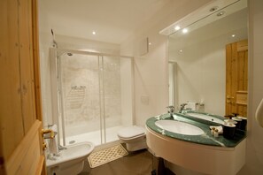 A bathroom with a glass-enclosed shower, a toilet, a sink with a green marble countertop, and a mirror. - Sport Hotel Vittoria (Vermiglio)