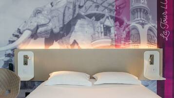 Une chambre d’hôtel avec un lit, deux interrupteurs d’éclairage fixés au mur et une grande fresque murale.