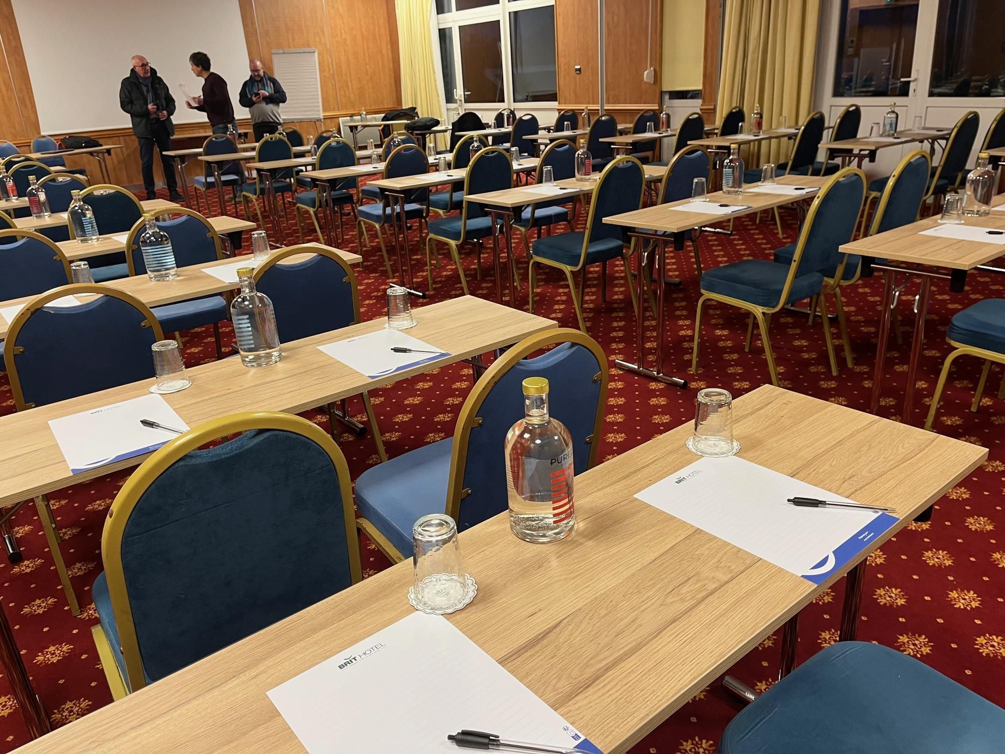 A conference room with rows of tables, chairs, and a whiteboard.