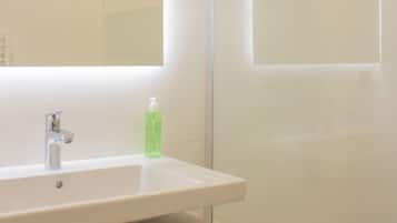 A modern bathroom with a glass shower enclosure, a white sink, and a mirror above it.