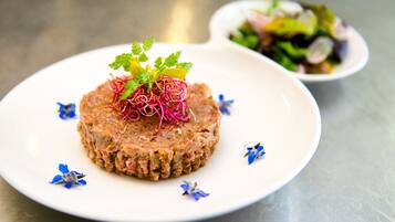 A plate of food with a garnish of greens and flowers, and a small bowl of salad in the background.