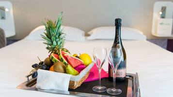 Ein Tablett mit Früchten, einer Champagnerflasche und zwei Gläsern auf einem Bett.