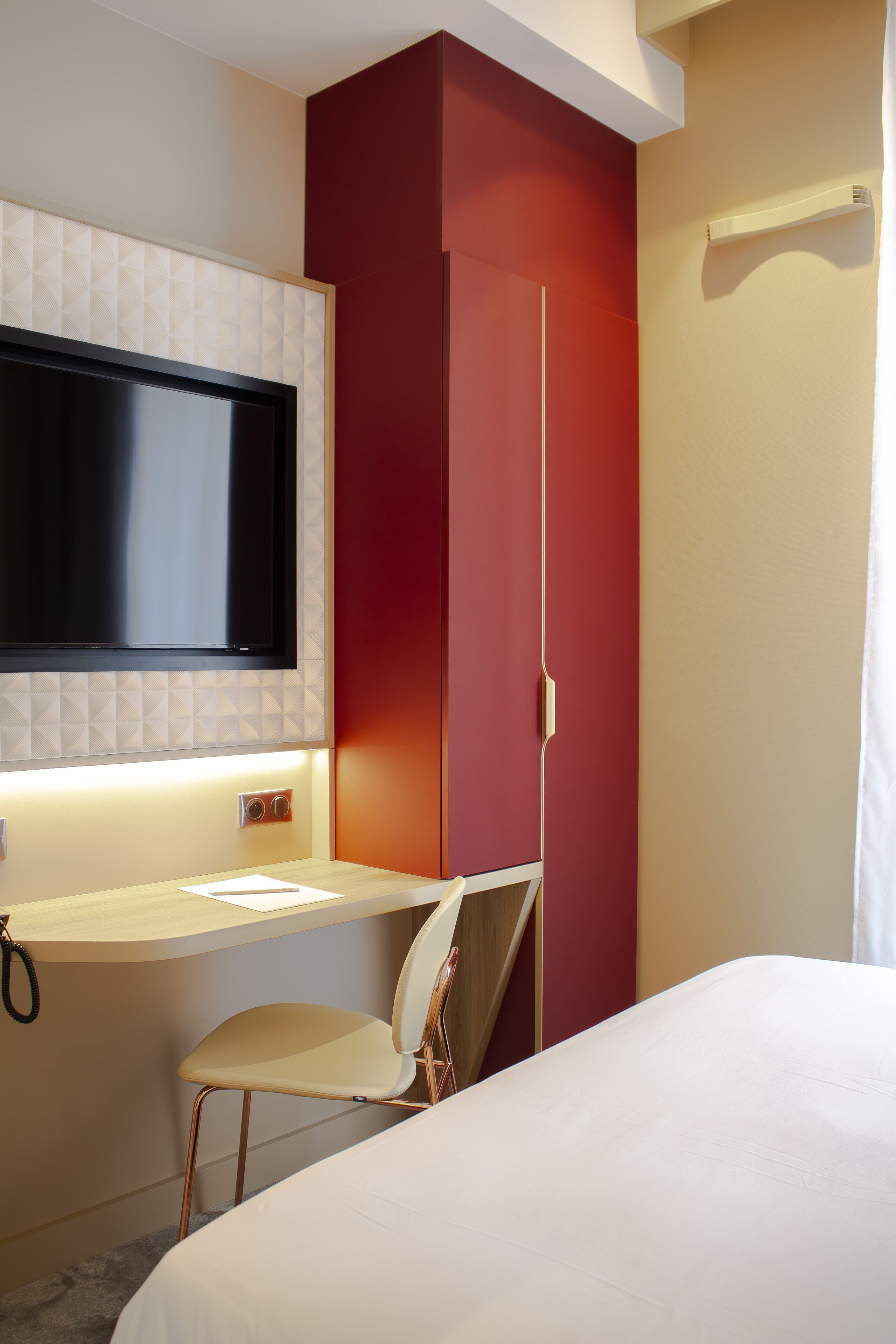 Una habitación de hotel con una cama, un escritorio, una silla, un televisor y un armario.