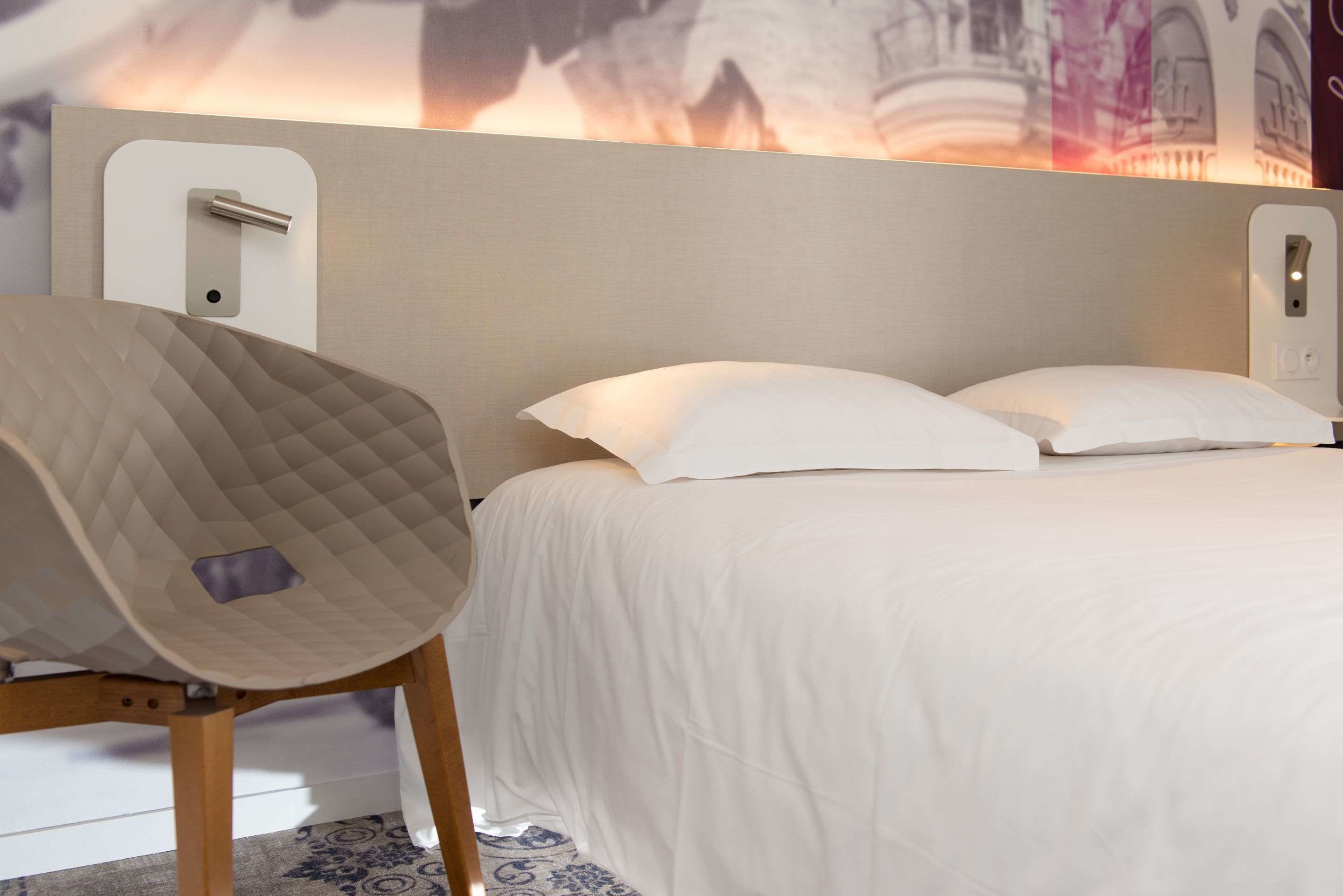 Ein Hotelzimmer mit einem Bett, einem Sessel und einer Wandleuchte.