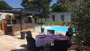 Ein Essbereich im Freien mit Pool und Liegestühlen im Hintergrund.