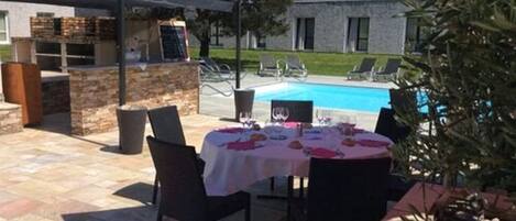 Ein Essbereich im Freien mit Pool und Liegestühlen im Hintergrund.