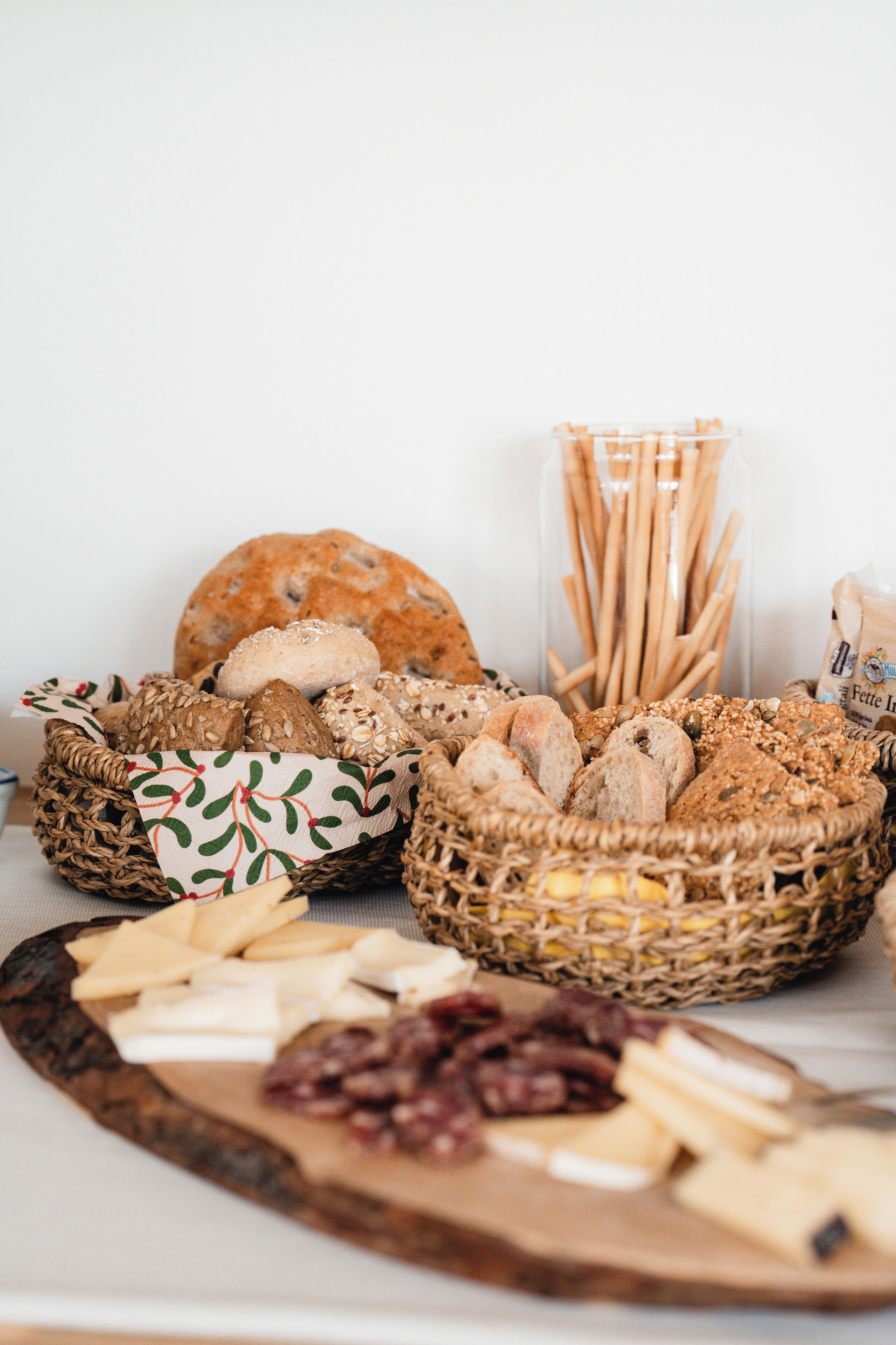 A variety of breads and cheeses on a wooden board.