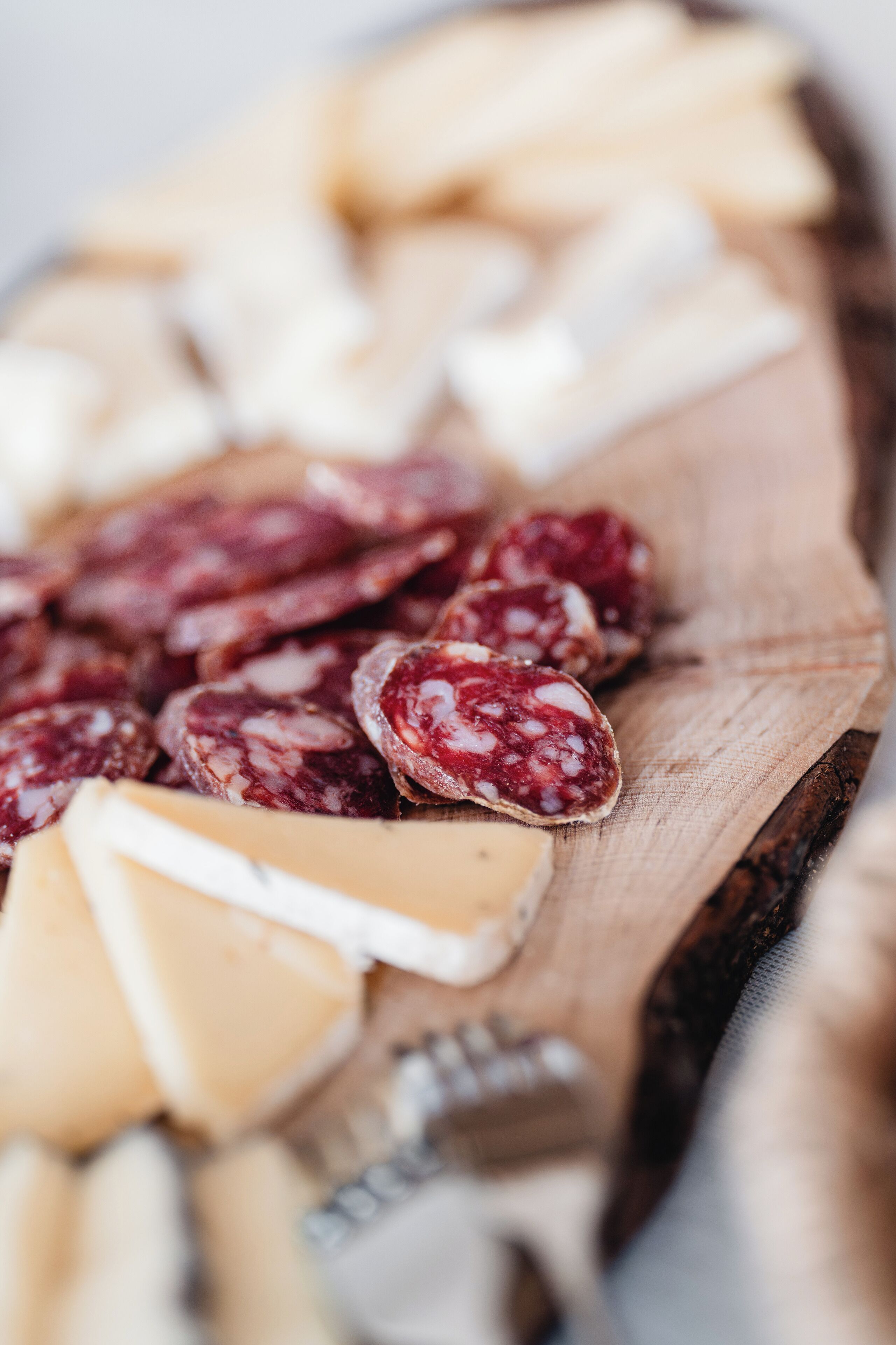 A wooden board with various types of cured meats and cheeses.