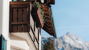 Un chalet traditionnel avec des balcons en bois, une vue sur la montagne et un ciel dégagé.