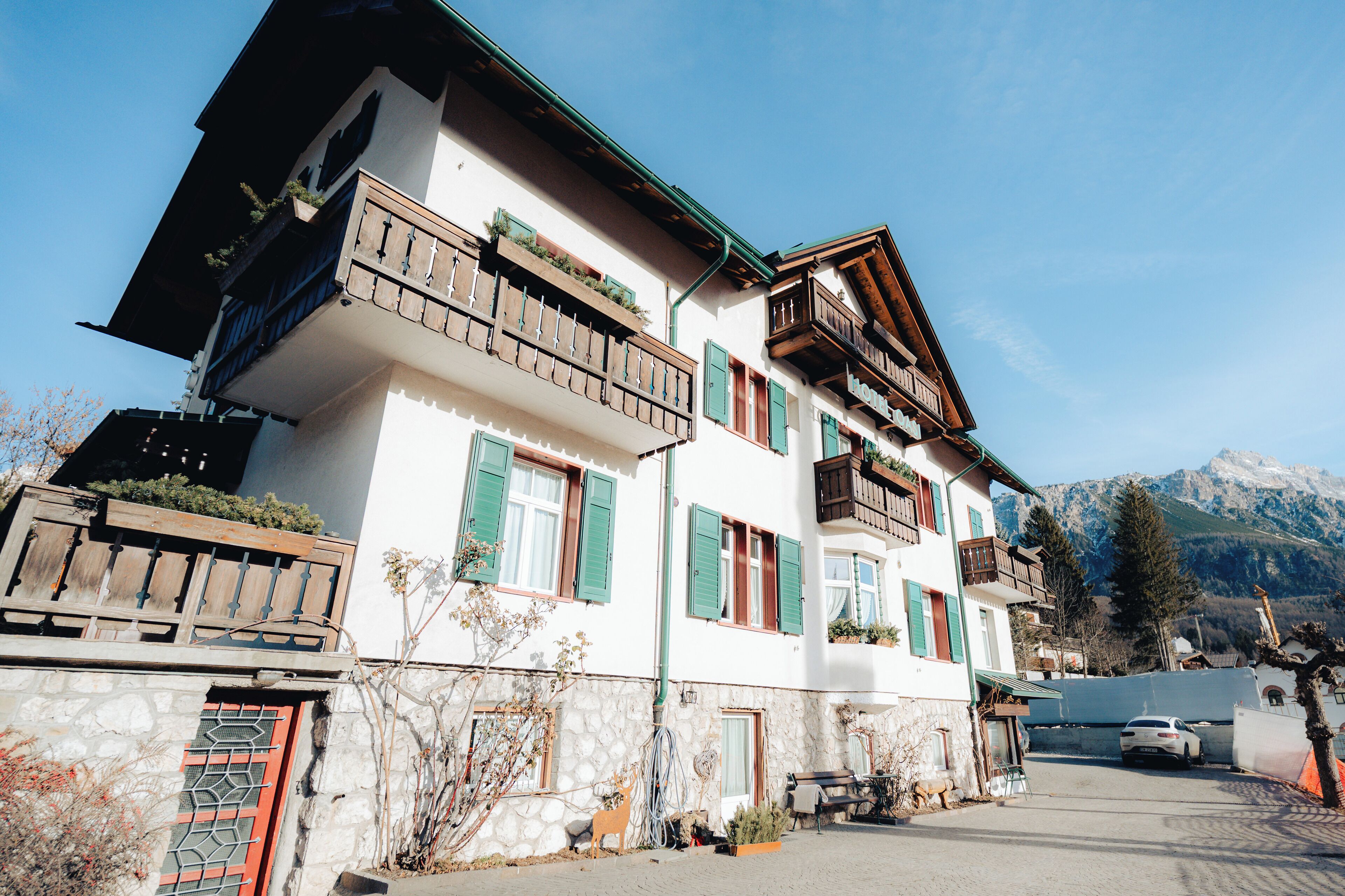 Un edificio de varios pisos con balcones, paredes de piedra y un paisaje montañoso de fondo.