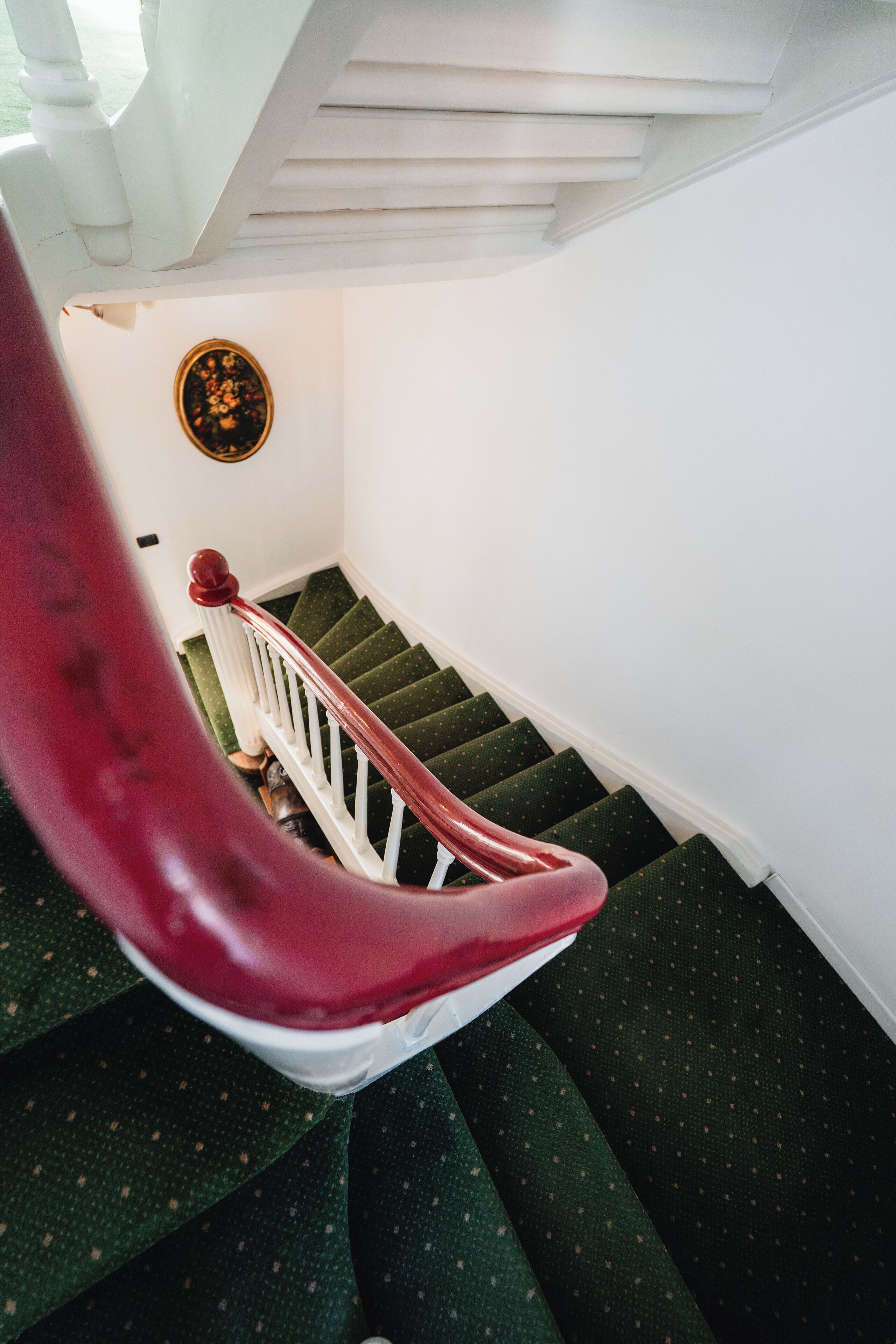 A staircase with green carpeted steps and a white railing.