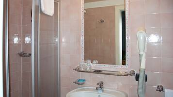 A bathroom with a shower, sink, and a mirror.