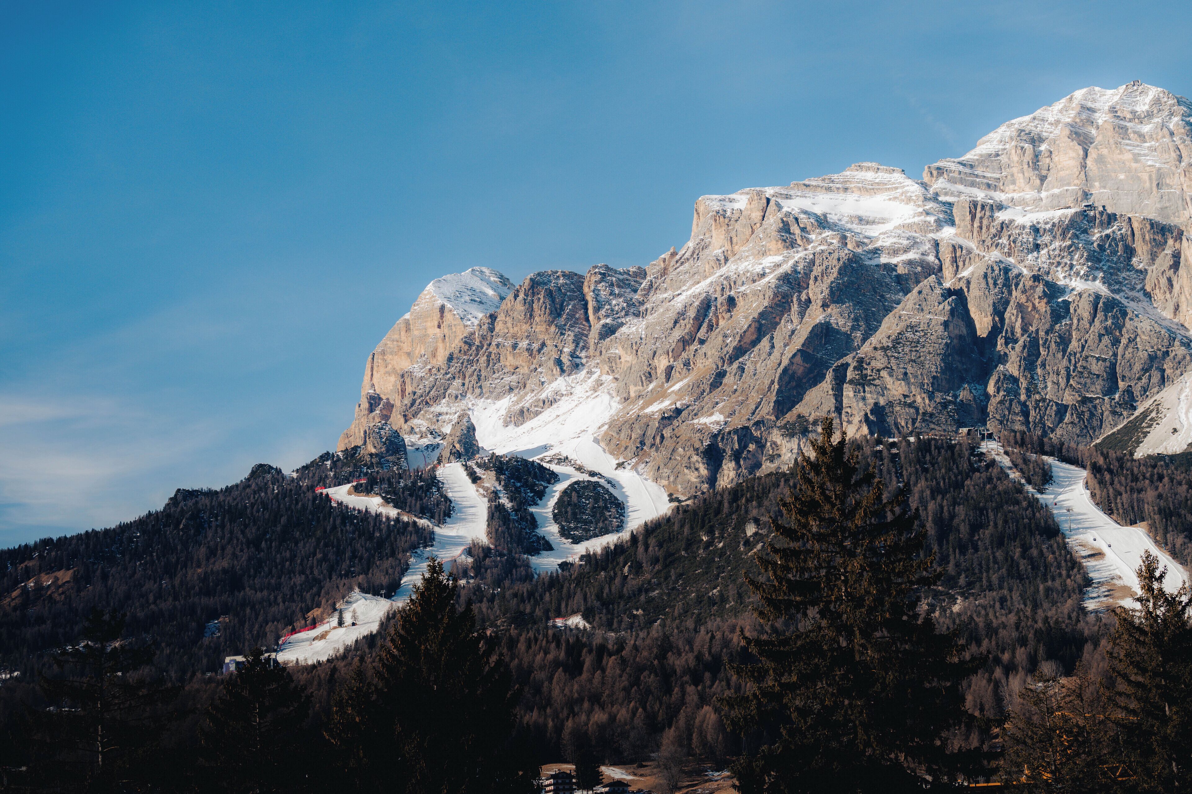 A mountainous landscape with a prominent peak, a ski trail, and dense forested areas.