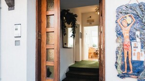 Une porte en bois qui donne sur un escalier recouvert d’une moquette verte.