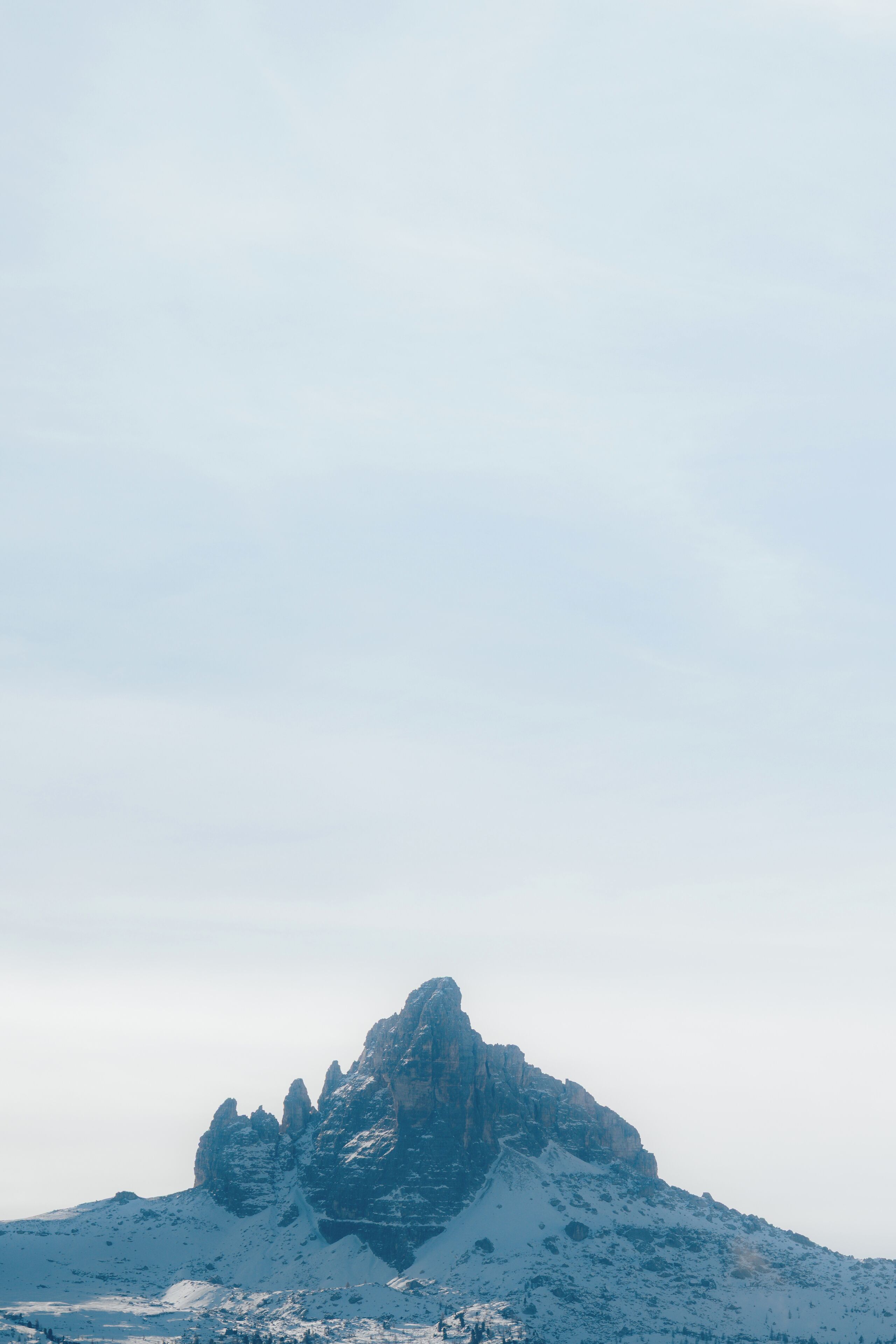 A snow-covered mountain peak with rugged terrain and a clear sky.
