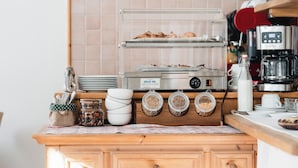 Un comptoir de cuisine avec une machine à café, des bocaux et une étagère remplie de produits de boulangerie.