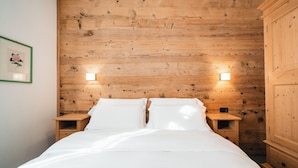 Une chambre à coucher avec une tête de lit en bois, deux tables de chevet et un lit avec une literie blanche.
