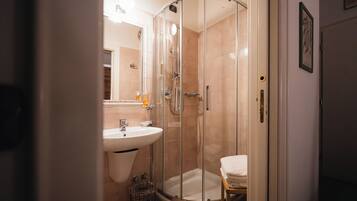 Un baño moderno con ducha acristalada, lavamanos e inodoro.