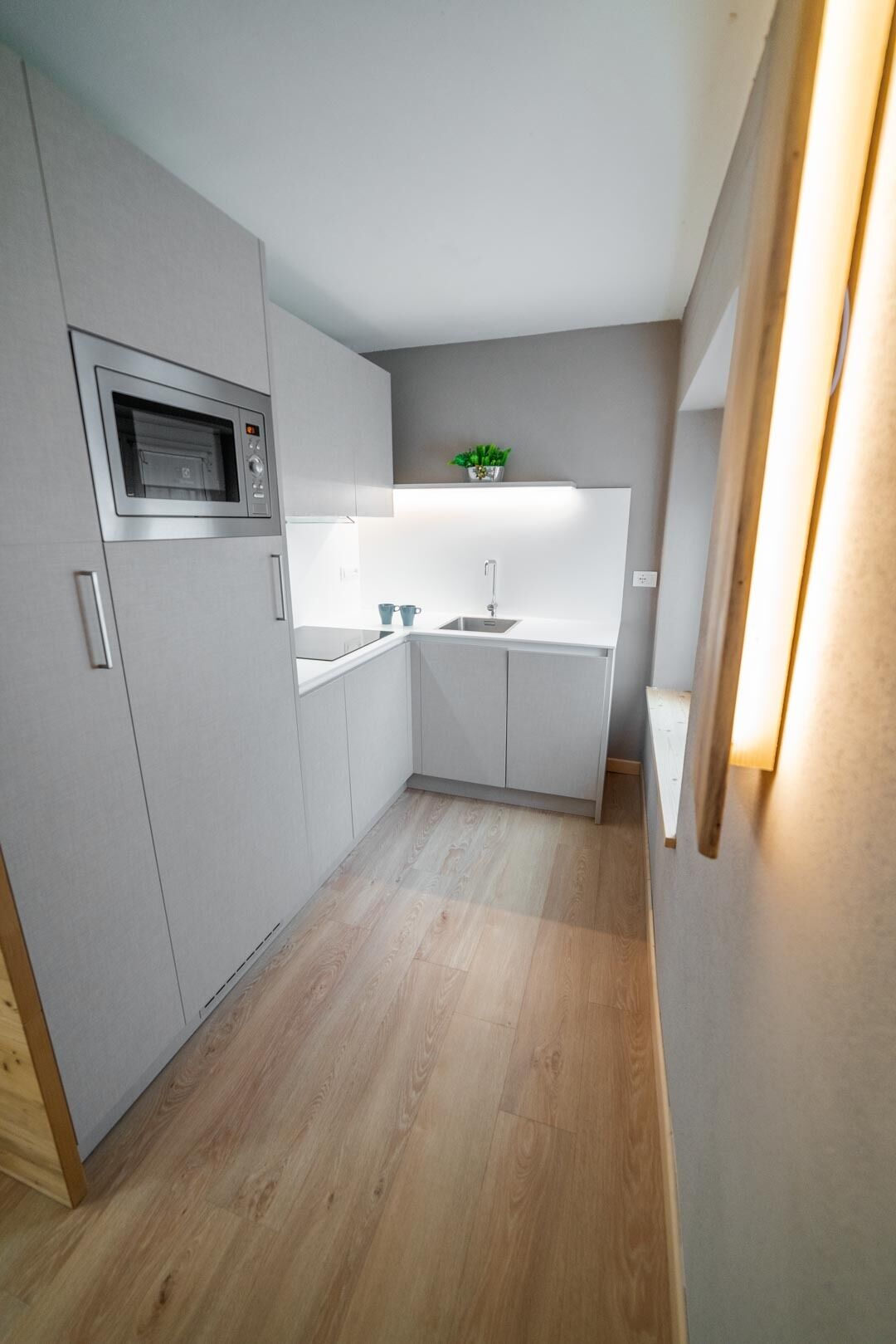 A modern kitchen with a built-in microwave, a sink, and a small countertop.
