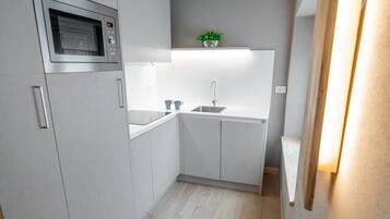 A modern kitchen with a built-in microwave, a sink, and a small countertop.