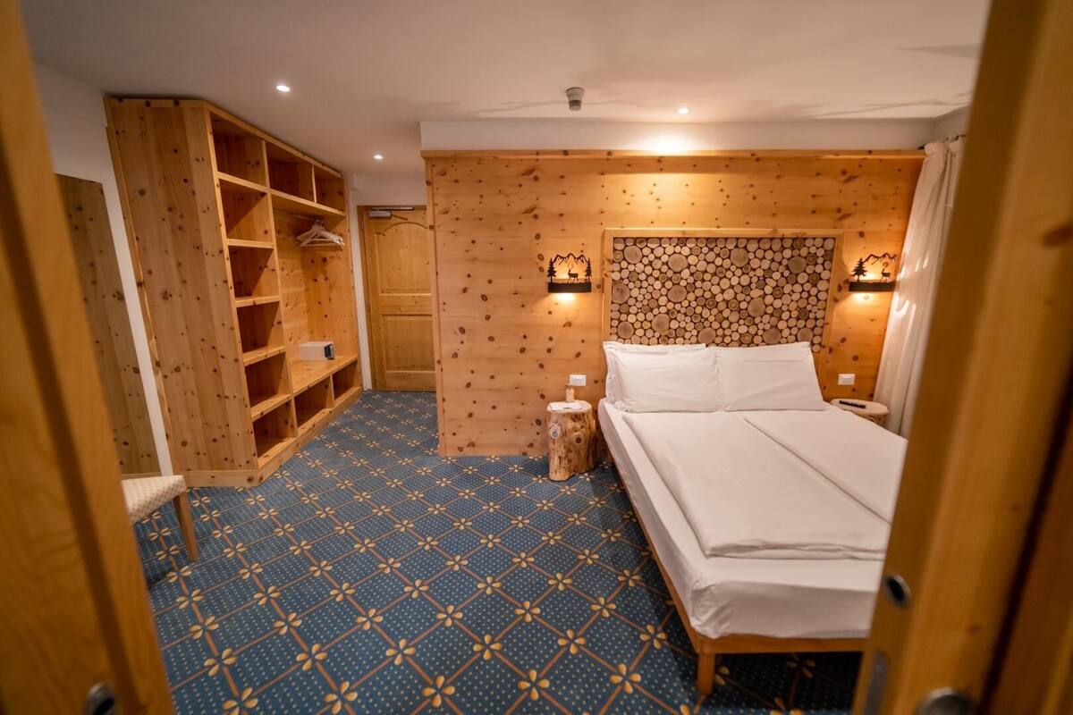 Una habitación con una cama, un armario de madera y una pared decorada con troncos.