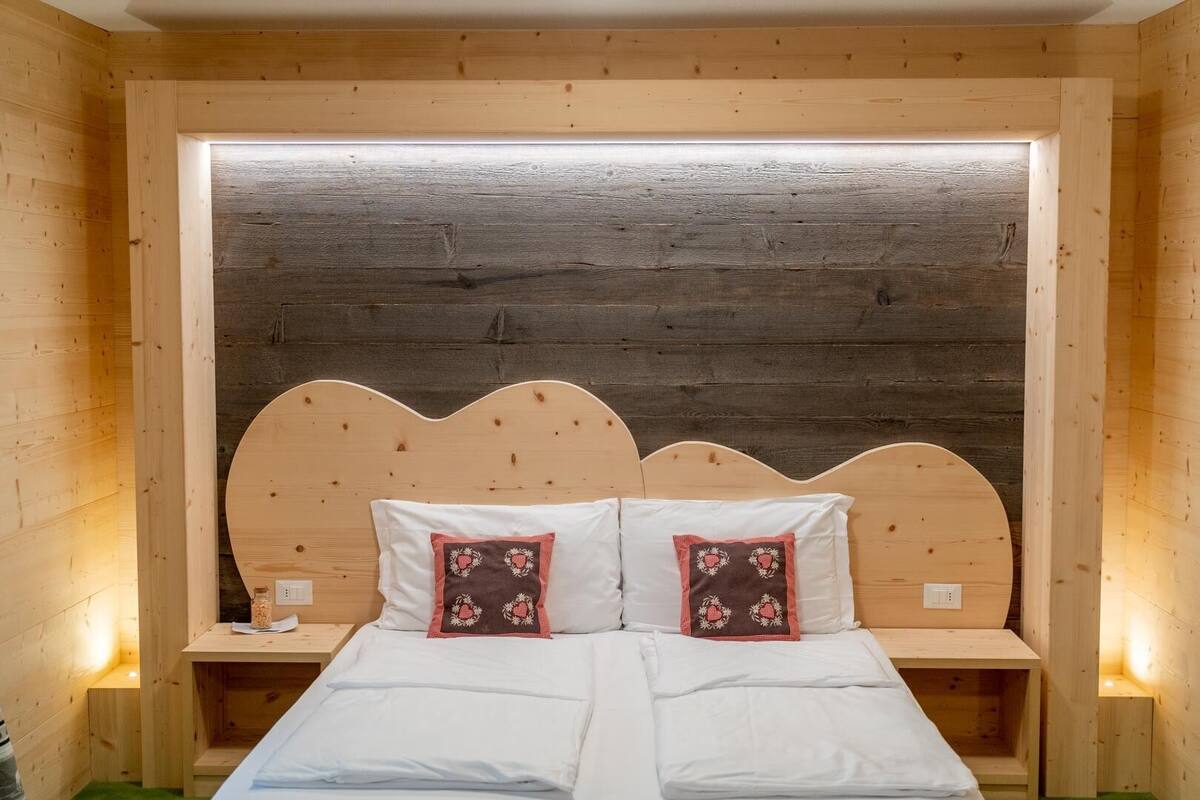 Una habitación de cabaña de madera con una cama, dos mesitas de noche y un ventanal grande.