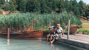 A wooden dock with a rowboat and a planter with flowers.