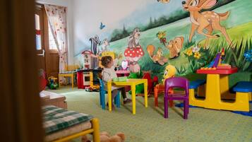 Children can play and learn in this vibrant playroom featuring a whimsical woodland mural and colorful furniture.