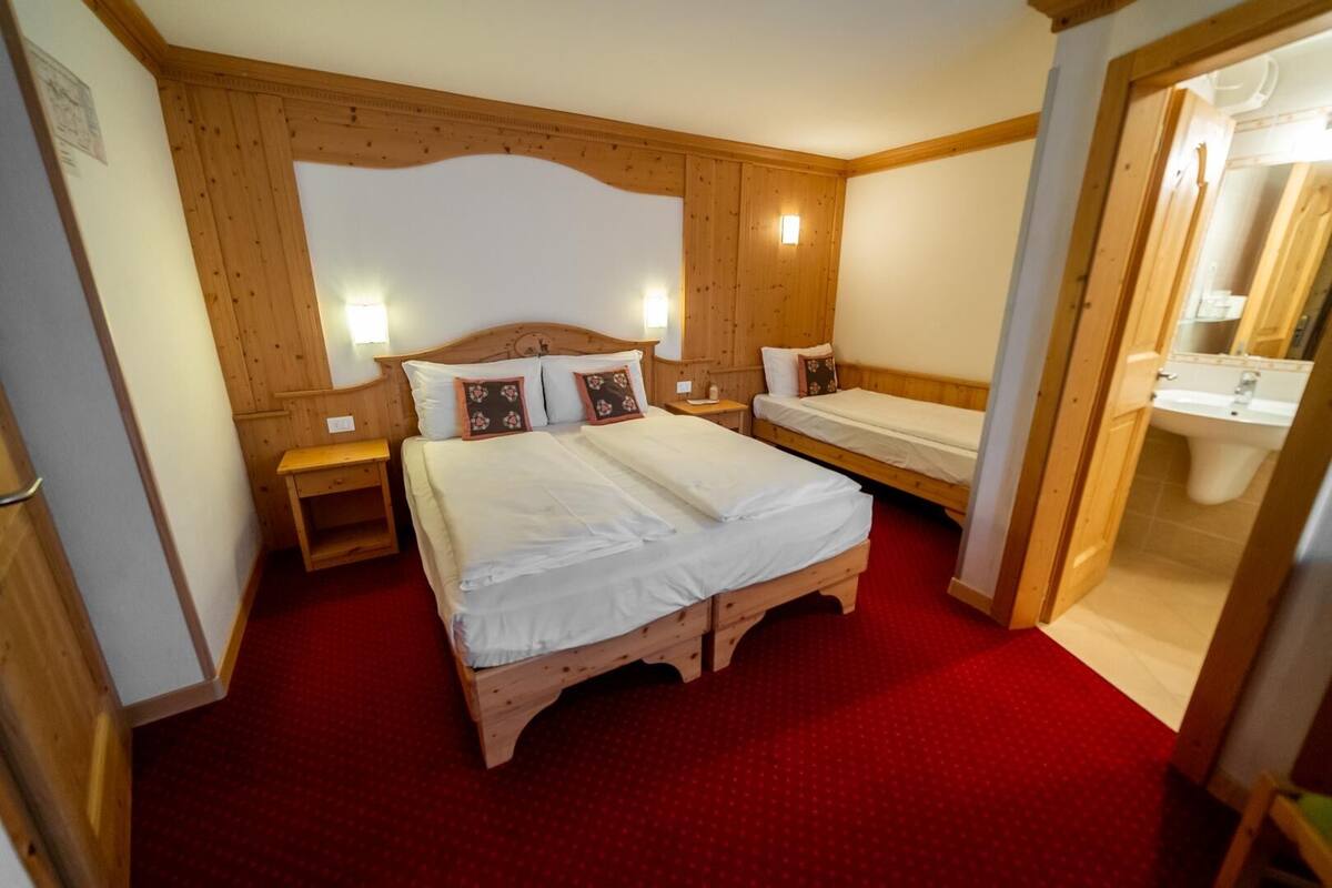 Un dormitorio con paneles de madera, una cama grande, dos mesitas de noche y una alfombra roja.