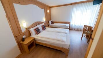 A room with two wooden beds, a wooden chair, and a small table.