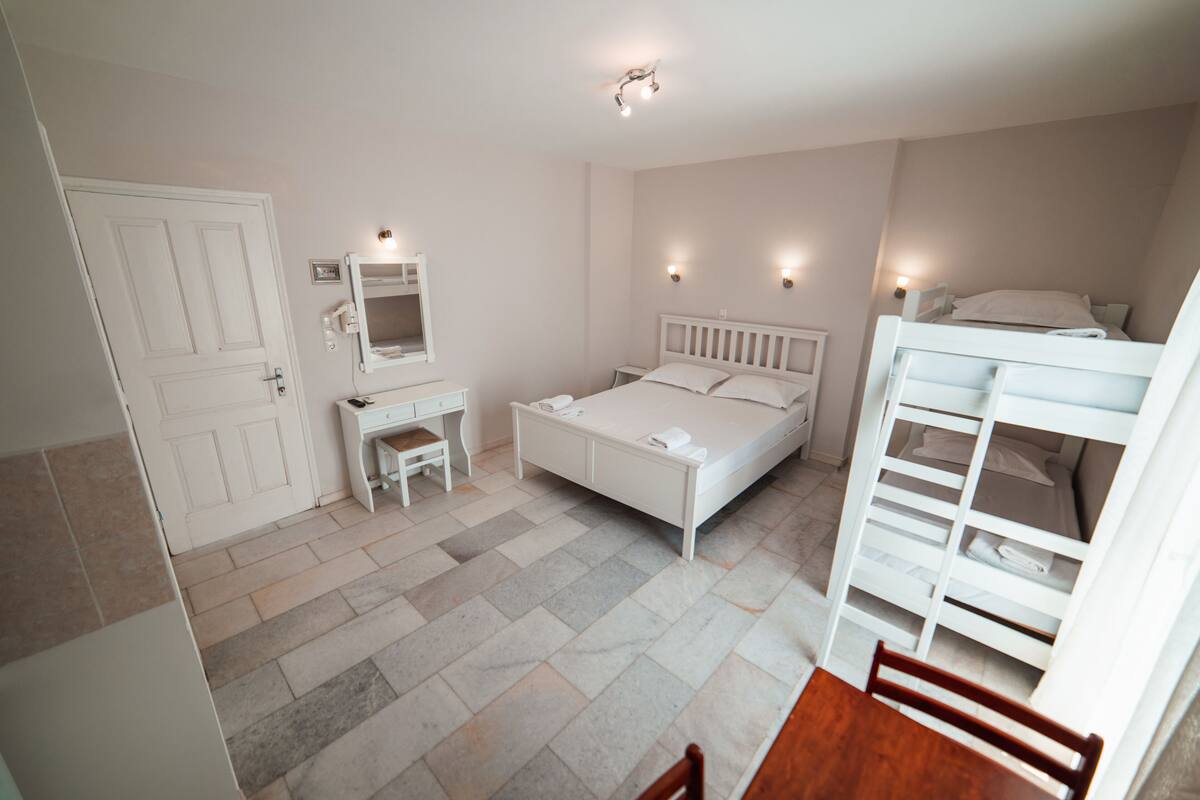 Quarto com cama, escrivaninha, cadeira, guarda-roupa e porta.