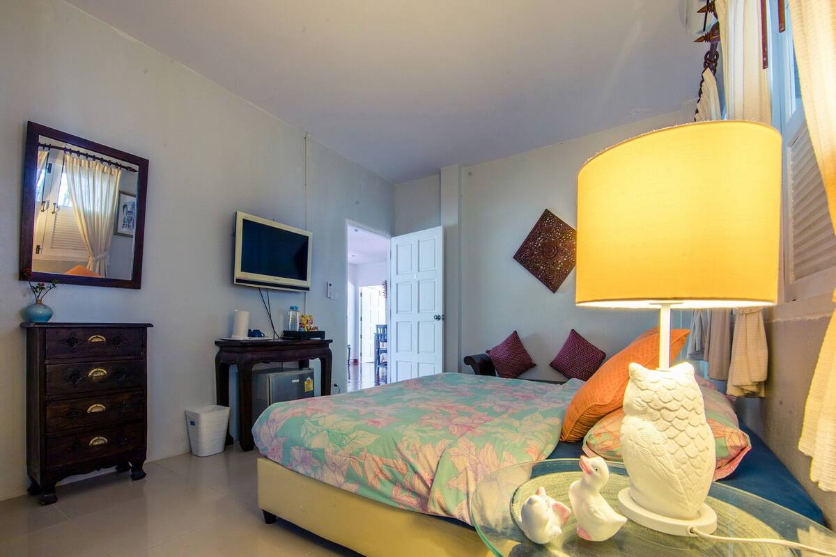 Una habitación de hotel con cama, televisión, cómoda y lámpara.
