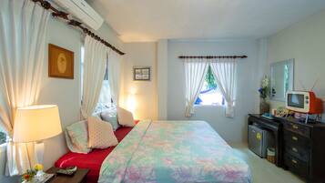 Een slaapkamer met een bed, een dressoir, een televisie en een raam met gordijnen.