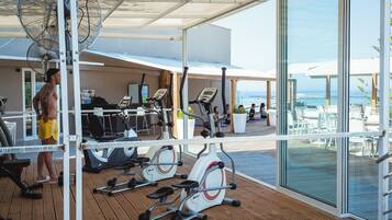 Ein Fitnessraum mit Trainingsgeräten und Blick auf den Ozean.