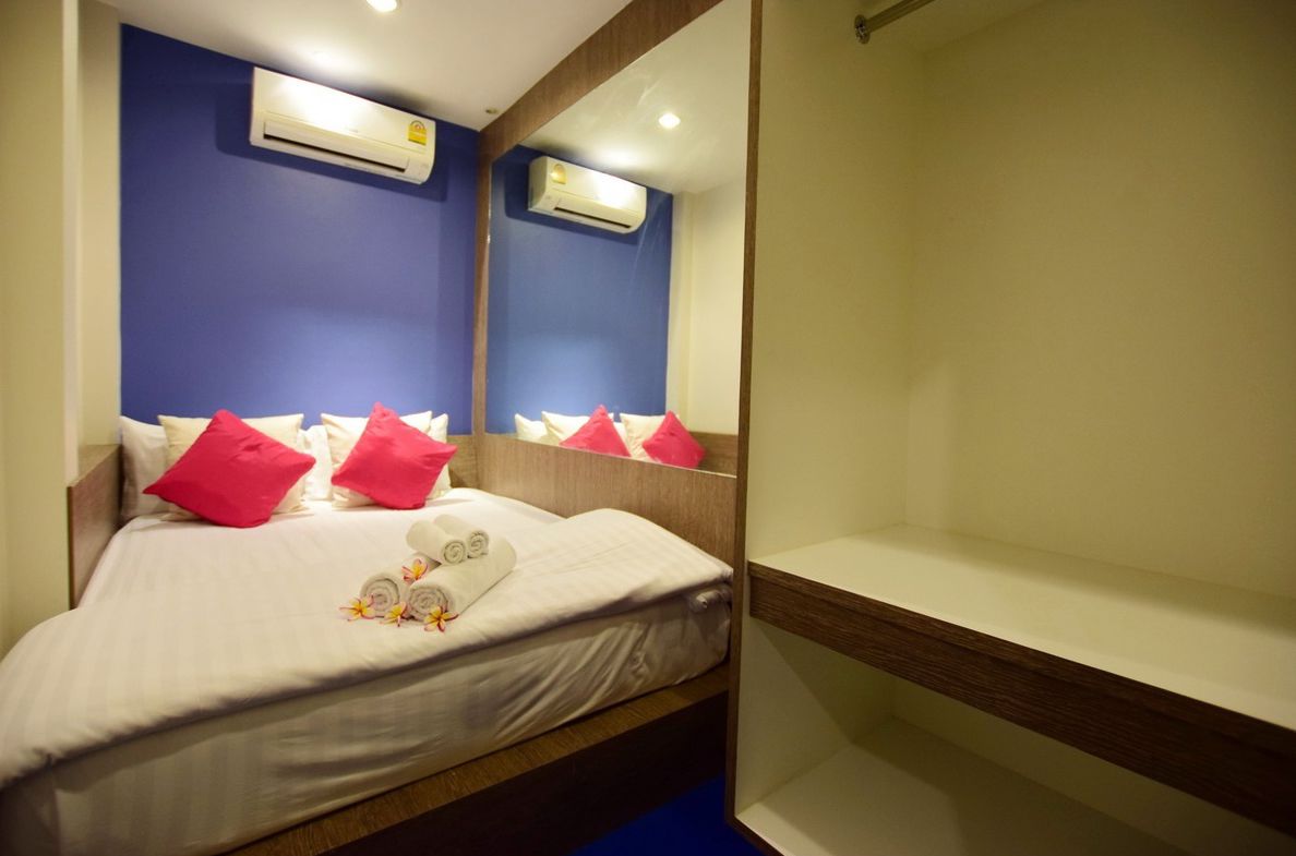 Una habitación de hotel con cama, almohadas, un espejo y un equipo de aire acondicionado.