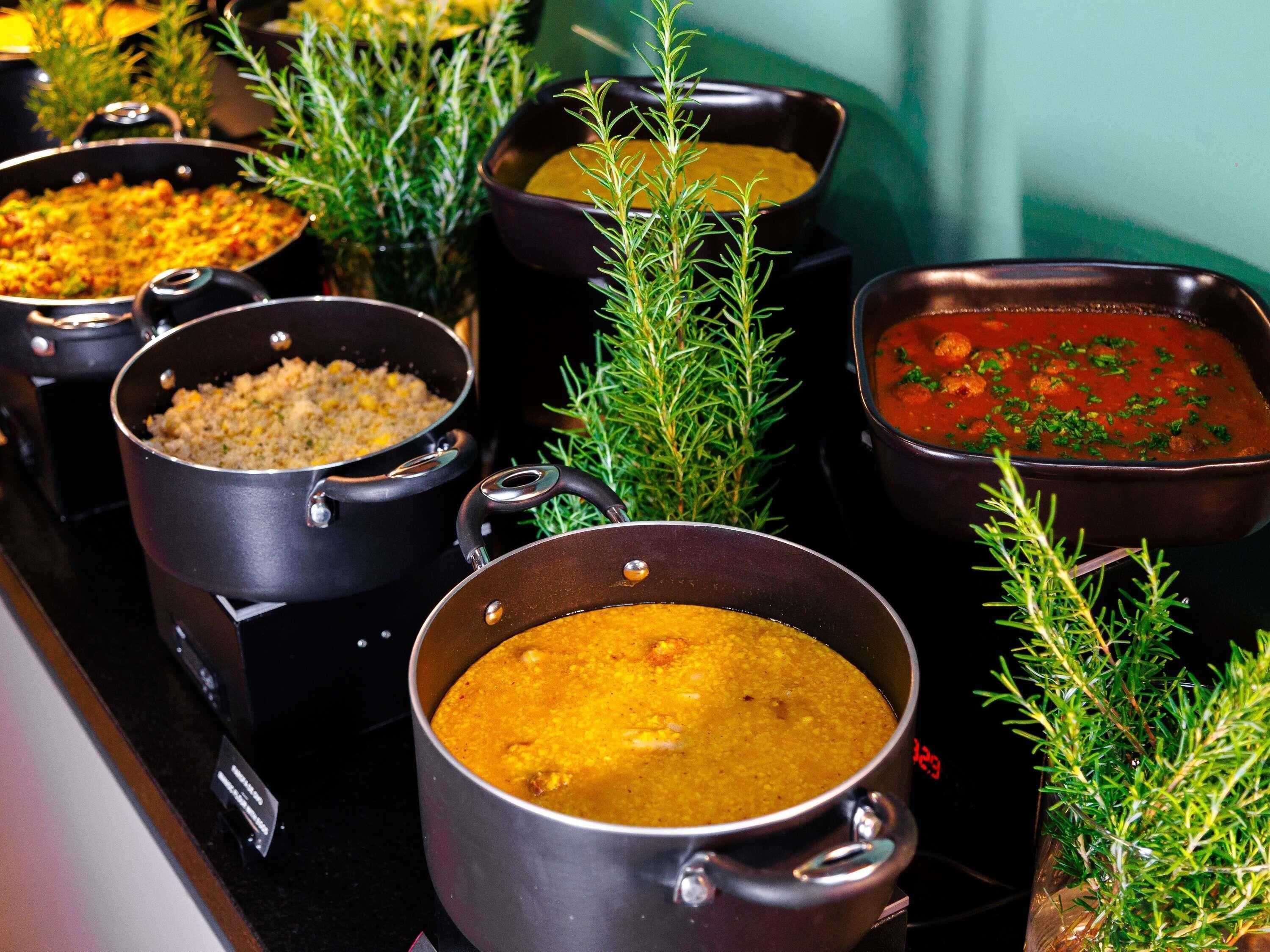 Uma cozinha com várias panelas no fogão, cada uma contendo pratos diferentes.