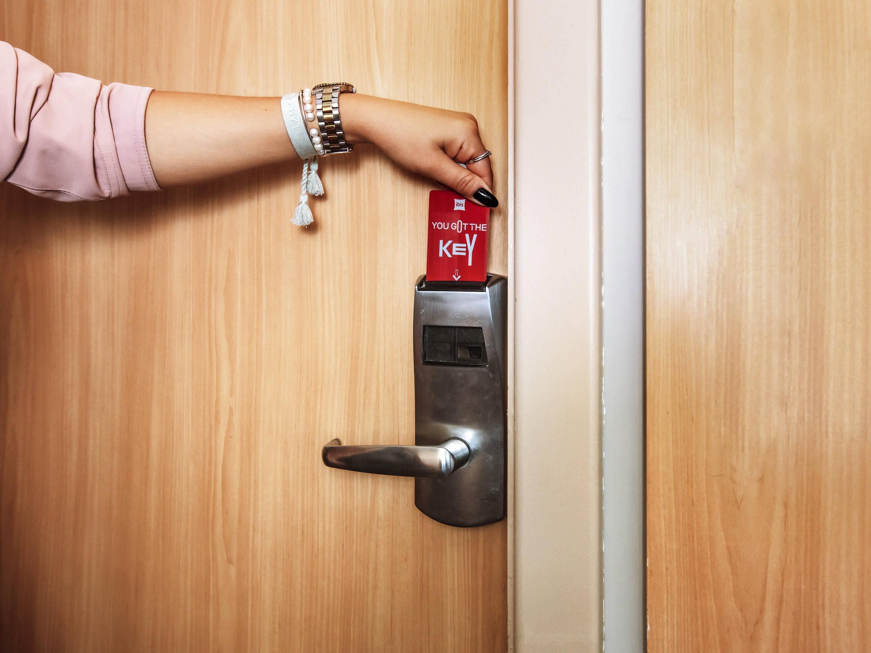 Une main insérant une carte à puce dans une serrure de porte.