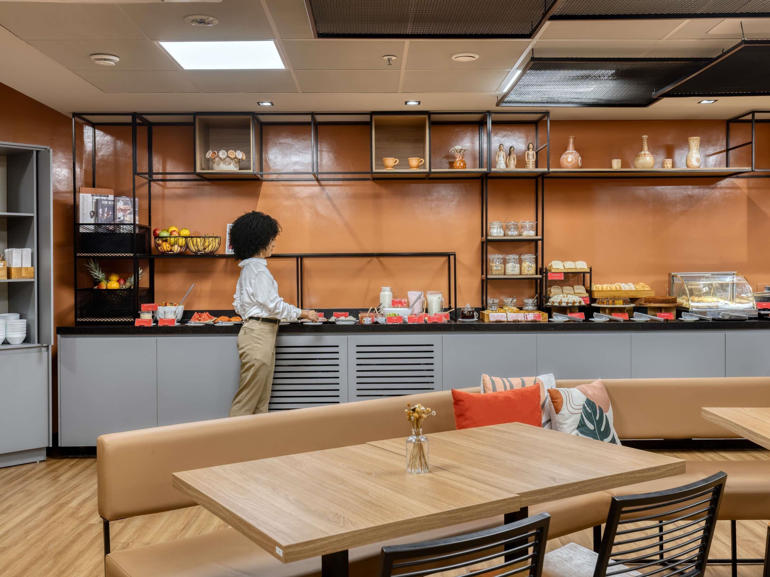 Un café moderne avec un comptoir, un espace salon et des étagères remplies de divers articles.