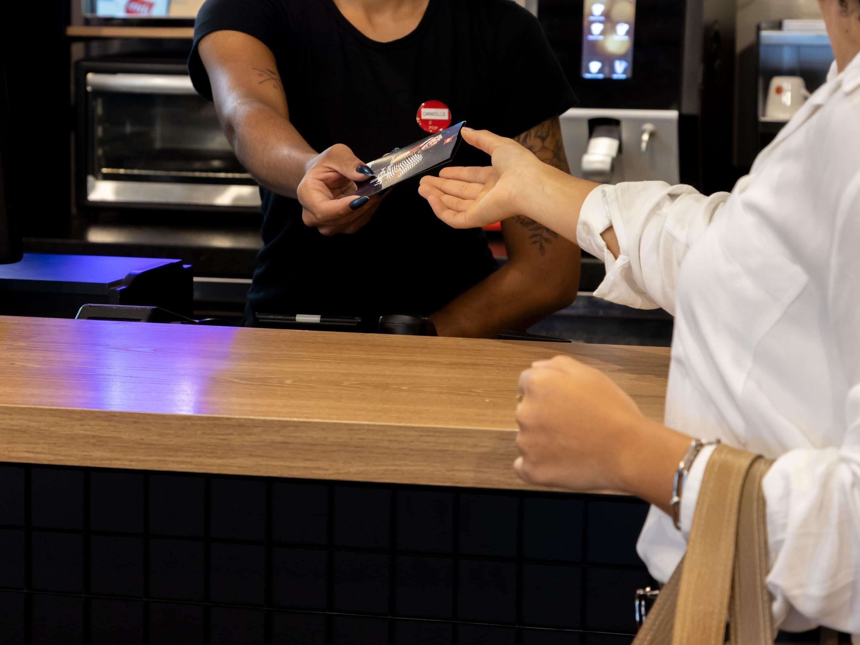 A person at a counter, possibly a restaurant or cafe, with a digital menu or card in hand.