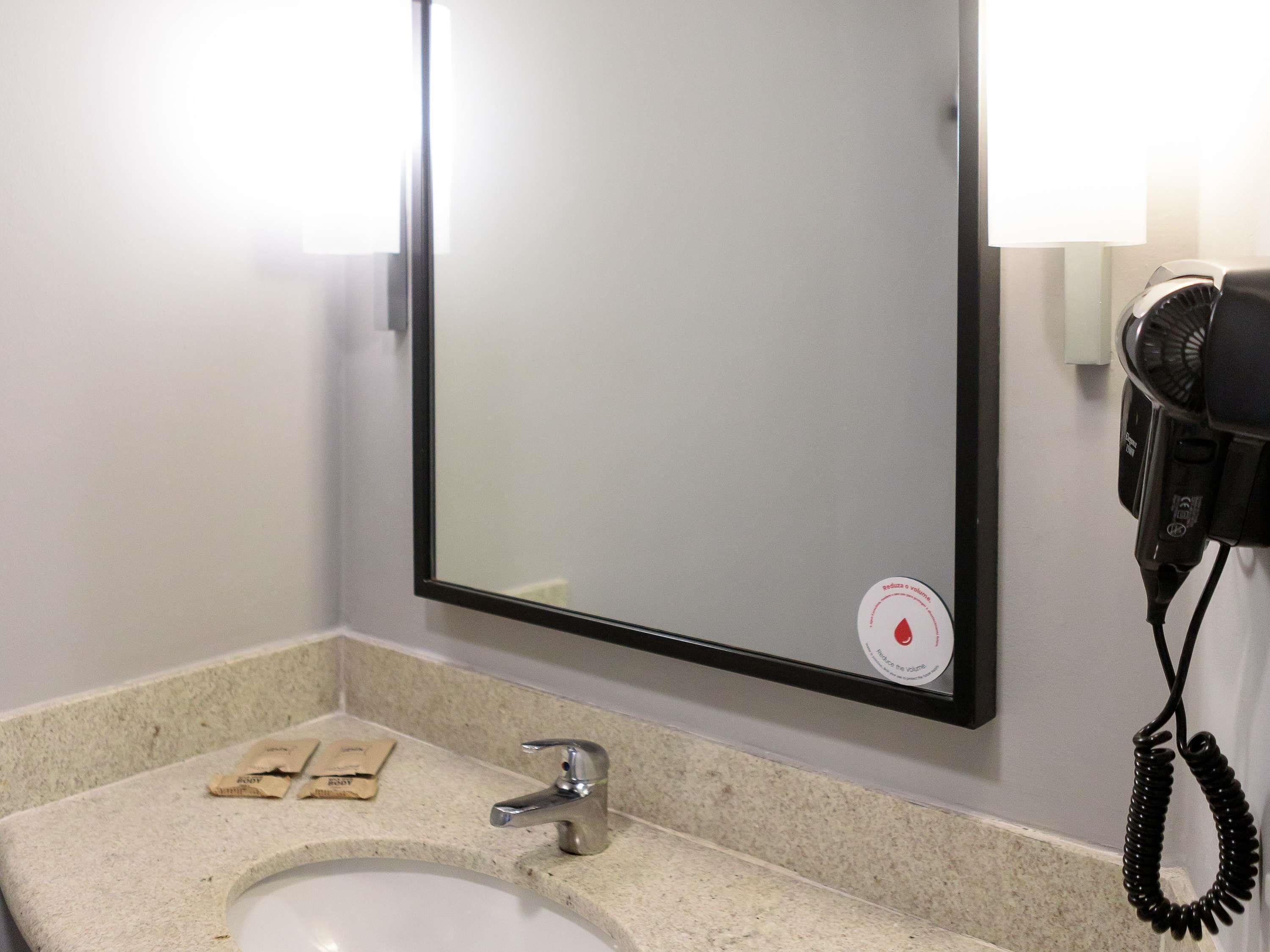 A bathroom with a sink, mirror, and hairdryer.