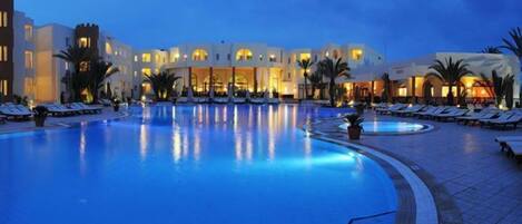 Una piscina techada, una piscina al aire libre, sombrillas