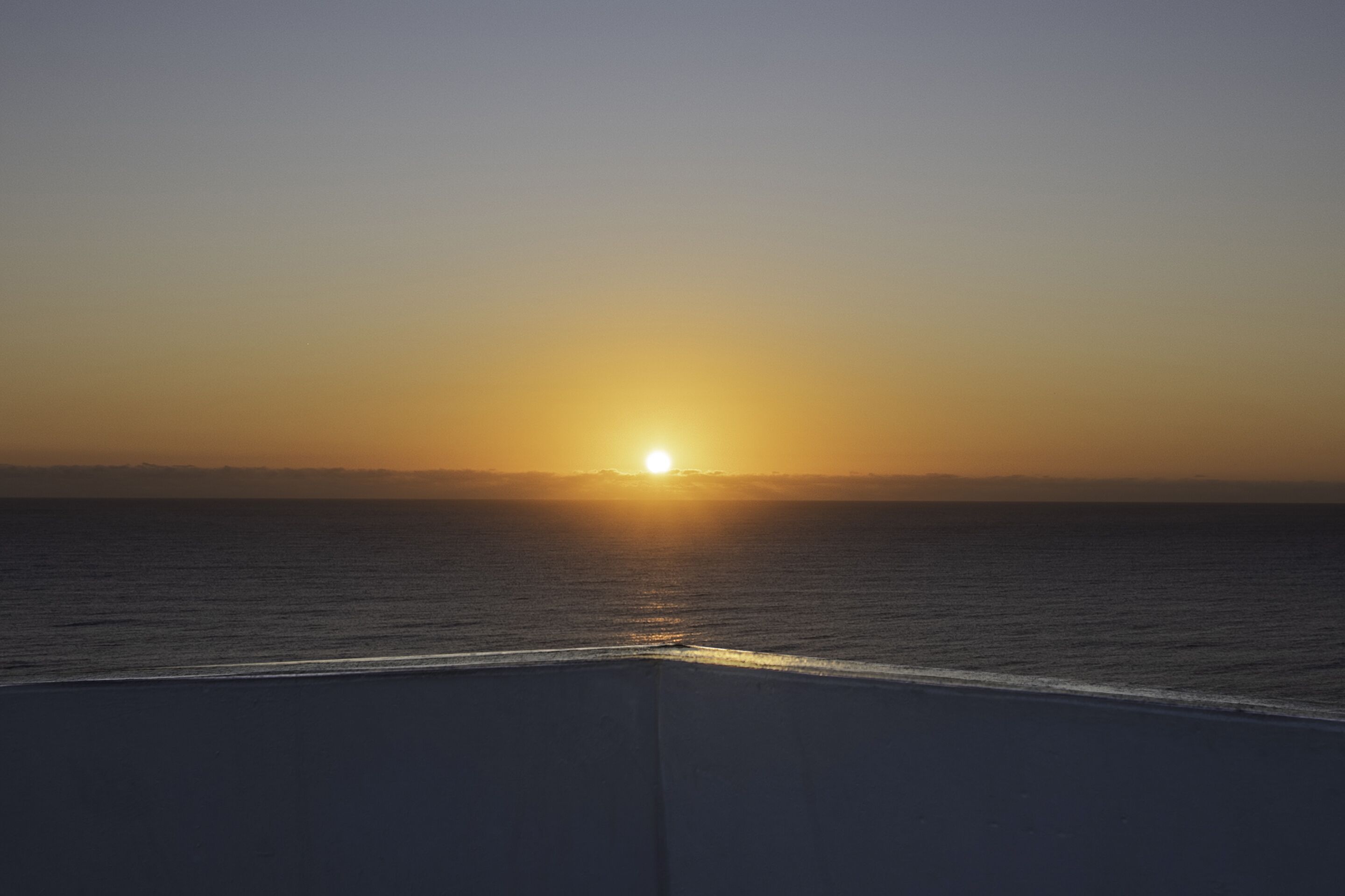 A sunset over the ocean with a clear sky.