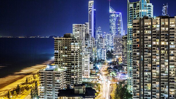 A nighttime cityscape with high-rise buildings, a beach, and a road with light trails. - Seacrest Beachfront Holiday Apartments (Surfers Paradise)